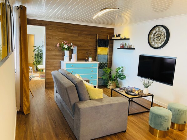 A modern living room with a sofa, a coffee table, a TV, and decorative items.