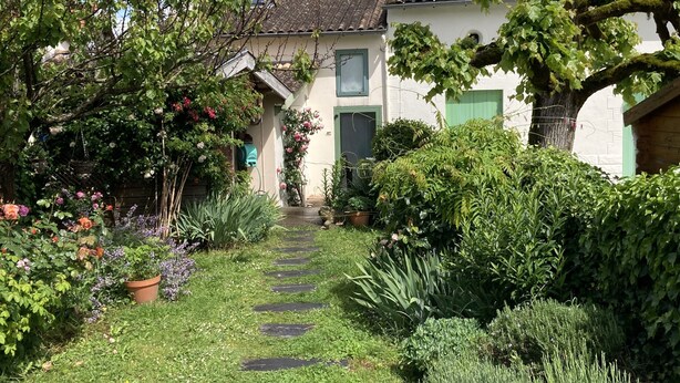A garden pathway leading to a house with a tiled roof, surrounded by lush greenery and flowering plants. - Maison Sainte Foy La Grande (Pineuilh)
