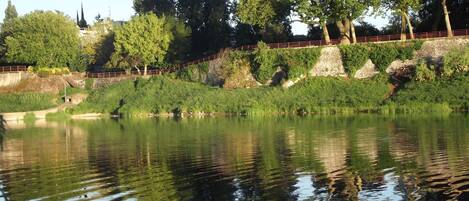 A calm river with a bridge and trees in the background.
