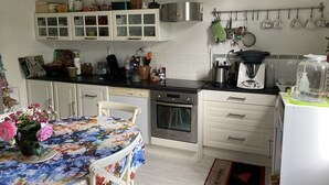 A kitchen with white cabinets, a coffee maker, and a kettle on the counter. - Maison Sainte Foy La Grande (Pineuilh)