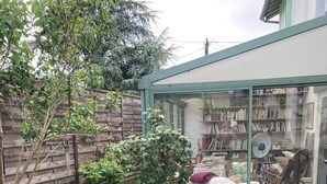 A green table with chairs in a garden area, surrounded by potted plants and a wooden fence. - Maison Sainte Foy La Grande (Pineuilh)
