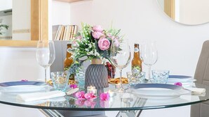 Una mesa de comedor dispuesta con platos, vasos y un jarrón de flores.