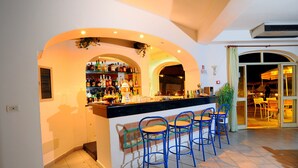 A bar area with a counter, blue bar stools, and a variety of bottles and glasses. - hotel park victoria (Forio)