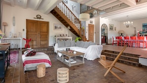 Un salón amplio con un sofá, una mesa de centro y una escalera que lleva a un piso superior.