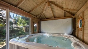 Un jacuzzi con panel de control, paredes de madera y un ventanal grande.