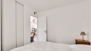 Ein Schlafzimmer mit einem Bett, einem Nachttisch mit Lampe und einer Tür zu einem Badezimmer.