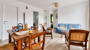 Ein Essbereich mit Holztisch und Stühlen, einem blauen Sofa und einer Küche im Hintergrund.