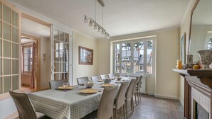 Comedor con una mesa dispuesta para seis comensales, chimenea y un ventanal con vistas al exterior.