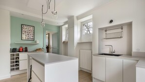 Una cocina moderna con armarios blancos, una isla central, un espacio para vinos empotrado y una ventana con vistas.