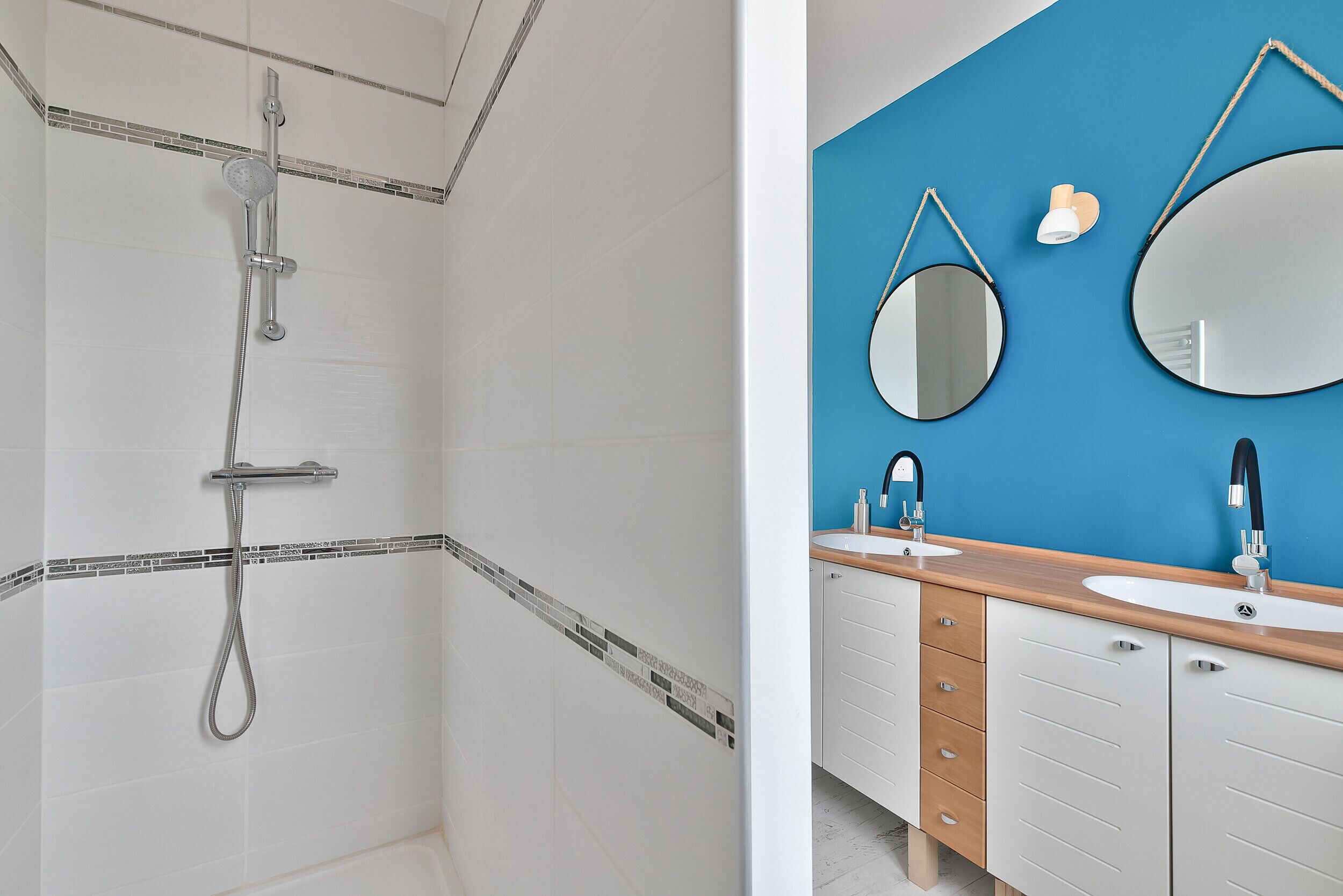 Un baño con ducha, lavamanos y dos espejos.