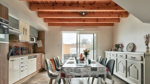 A modern kitchen with white cabinets, a microwave, and a dining area with a table set for four.