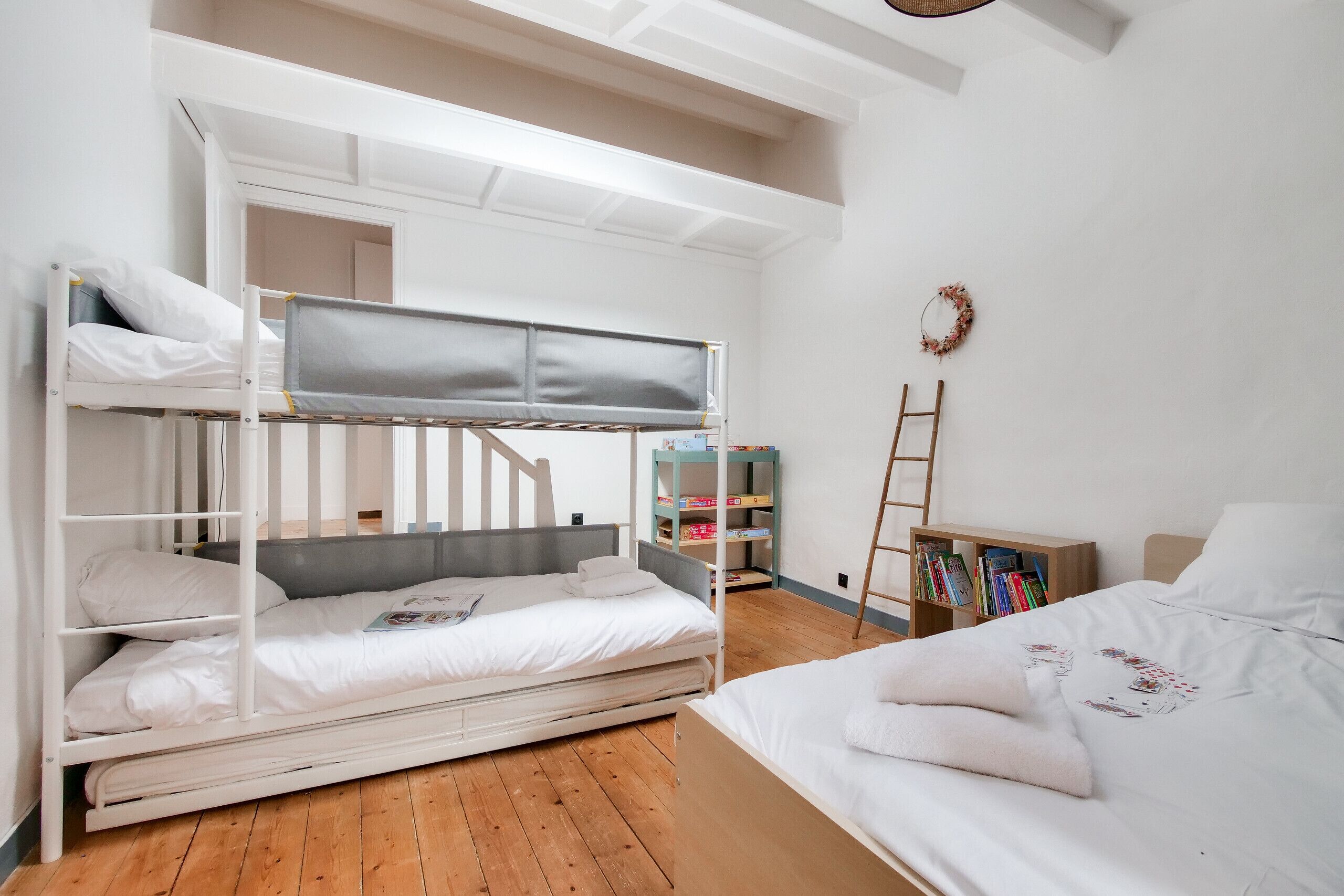 Habitación con literas, estantería y escalera.