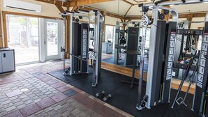 Una palestra con diverse macchine per esercizi, una porta che dà sull'esterno e un piccolo armadietto.