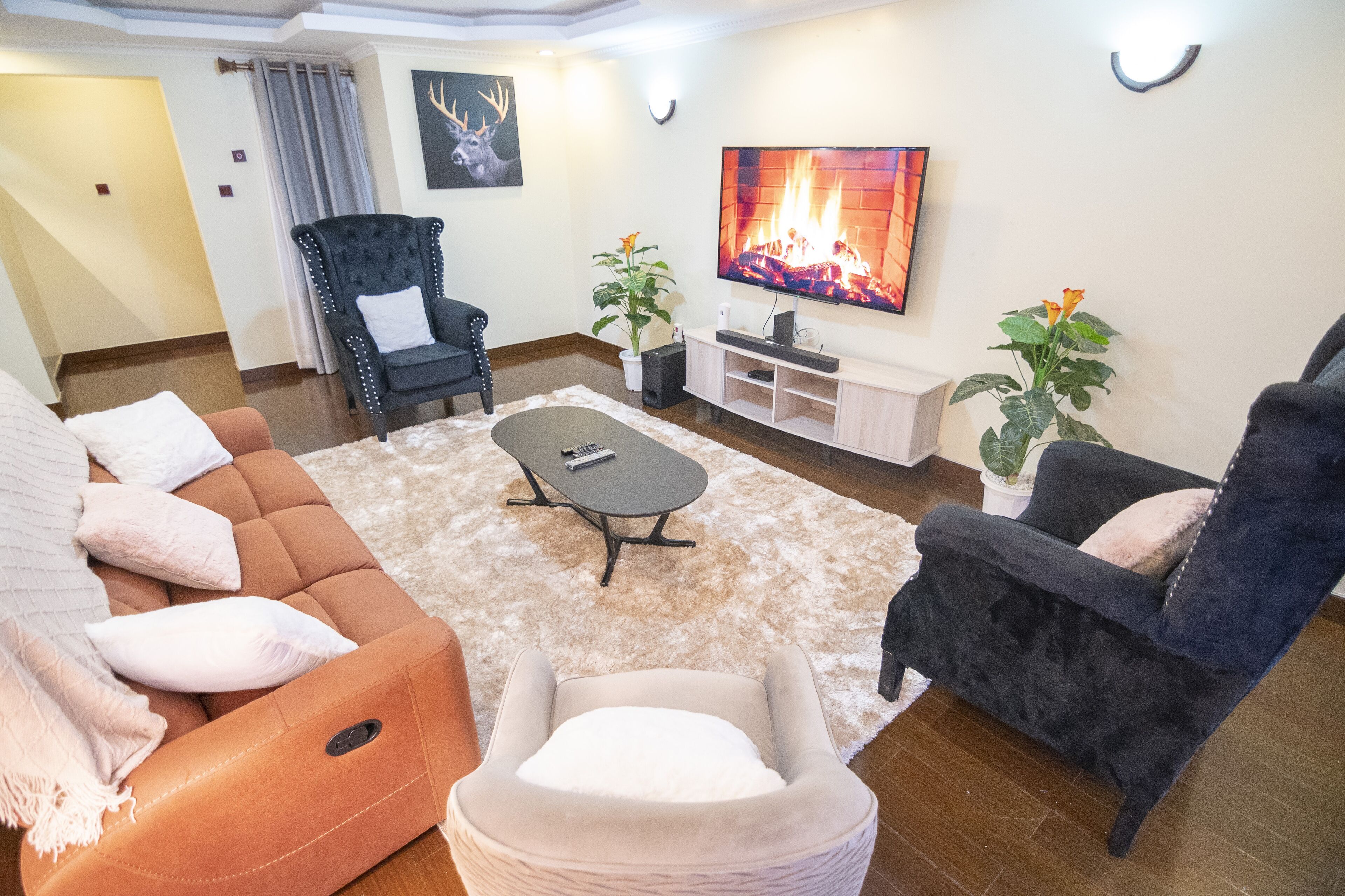 A living room with a sofa, armchairs, a coffee table, and a TV.