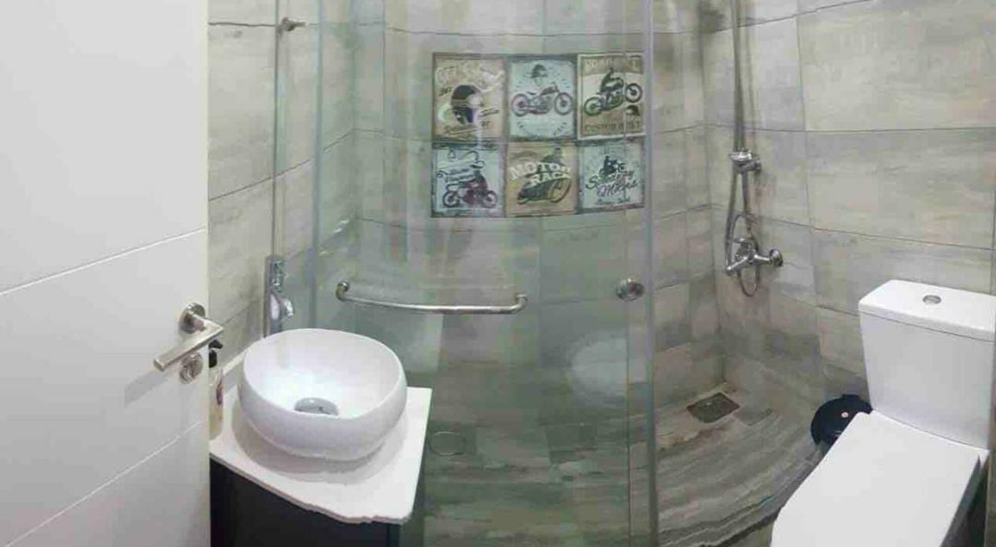 A bathroom with a glass-enclosed shower, a white sink, and a toilet.