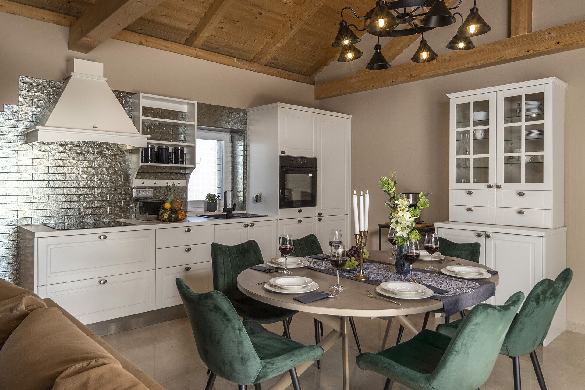 A modern kitchen with white cabinetry, a stone backsplash, and a dining area with a round table set for six.