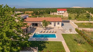 Eine Villa mit Swimmingpool, einer überdachten Terrasse und Blick auf die umliegende Landschaft.