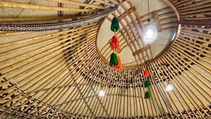 Een grote, ronde houten constructie met een hoge plafond en hangende decoraties, gevuld met mensen die aan tafels zitten, bedekt met witte tafelkleden, en een maaltijd nuttigen.