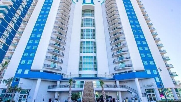 A high-rise hotel with a central atrium, multiple balconies, and a modern architectural design. - Budget Friendly Condo for 2 in Myrtle Beach, Walk to the Waves! (Myrtle Beach)