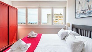 Una camera d'albergo con un letto, un armadietto rosso e una finestra vista città.