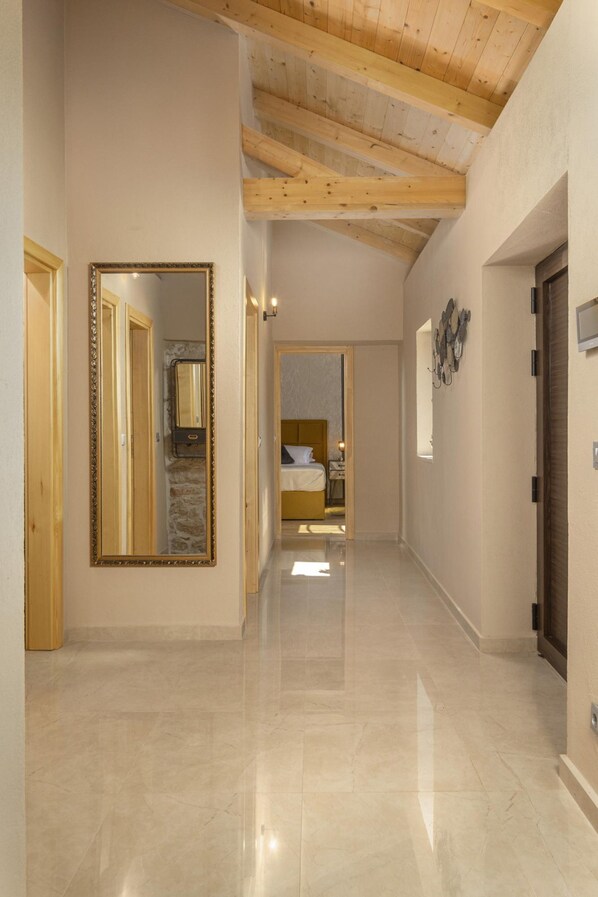 A hallway with a polished floor, wooden ceiling beams, and a large mirror.