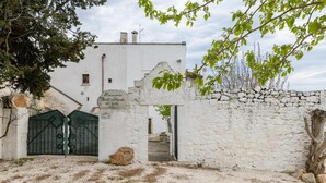 A historic building with a stone wall and a green gate, featuring a stone plaque with inscriptions. - Ilarius Country House by Wonderful Italy (Ostuni)