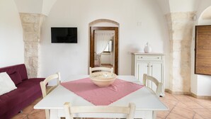 A dining area with a table, chairs, a bowl, a television, and a mirror. - Ilarius Country House by Wonderful Italy (Ostuni)