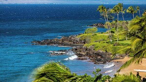 A coastal landscape with clear blue waters, rocky shoreline, and palm trees. - Polo Beach Club 106 | Beachfront Wailea Condo with Direct Beach Access (Wailea)