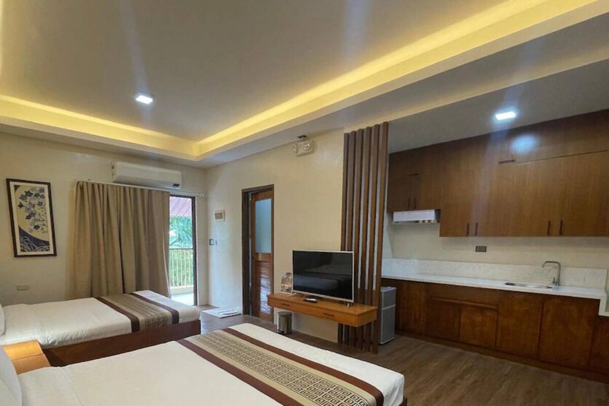 Une chambre d’hôtel avec deux lits, une télévision, une petite kitchenette et une salle de bain.