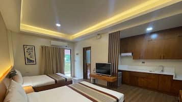 Habitación de hotel con dos camas, televisión, kitchenette pequeña y baño.