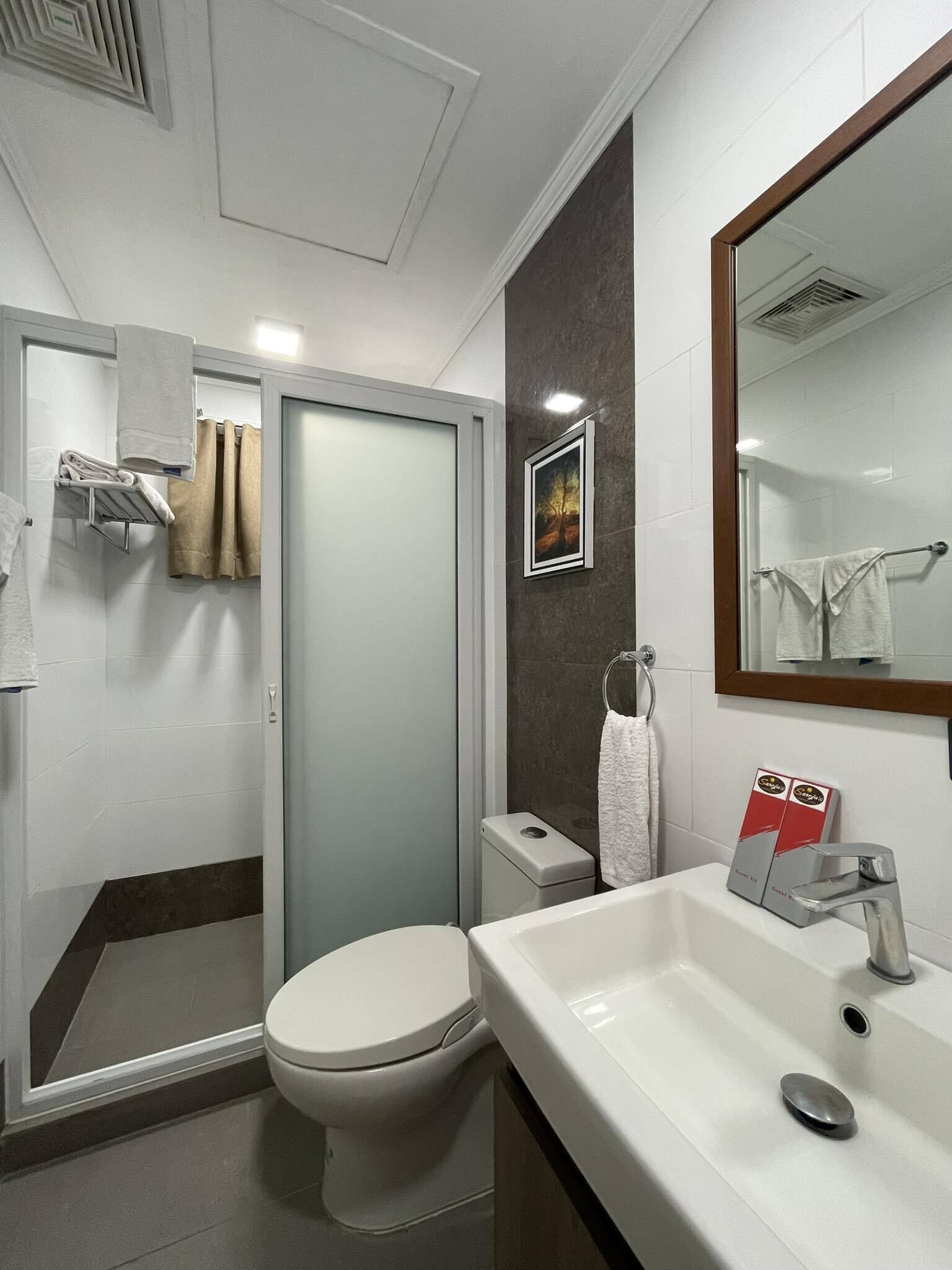 A modern bathroom with a toilet, shower, and sink.