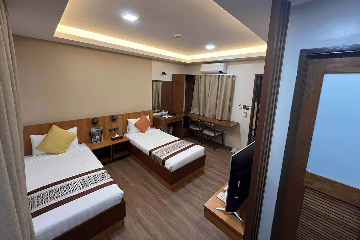 Une chambre d’hôtel avec deux lits, un bureau, une télévision et un appareil de climatisation.