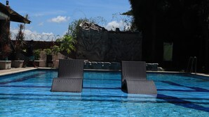 Une piscine avec deux chaises longues, un mur d’escalade et un ciel dégagé.