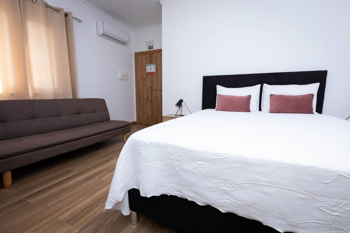 Ein Schlafzimmer mit einem Bett, einem Sofa und Holzboden.