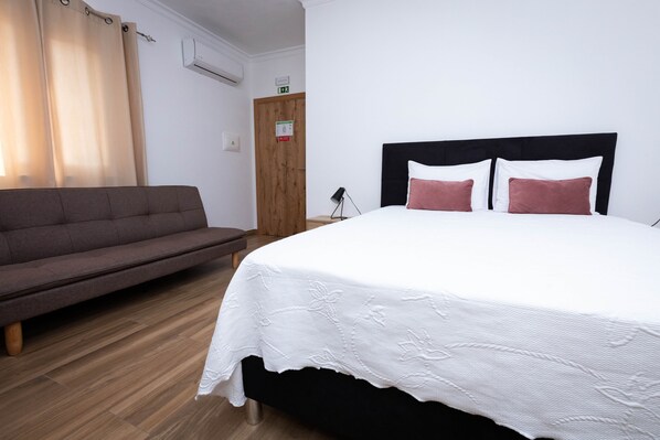 Una camera da letto con un letto, un divano e un pavimento in legno.