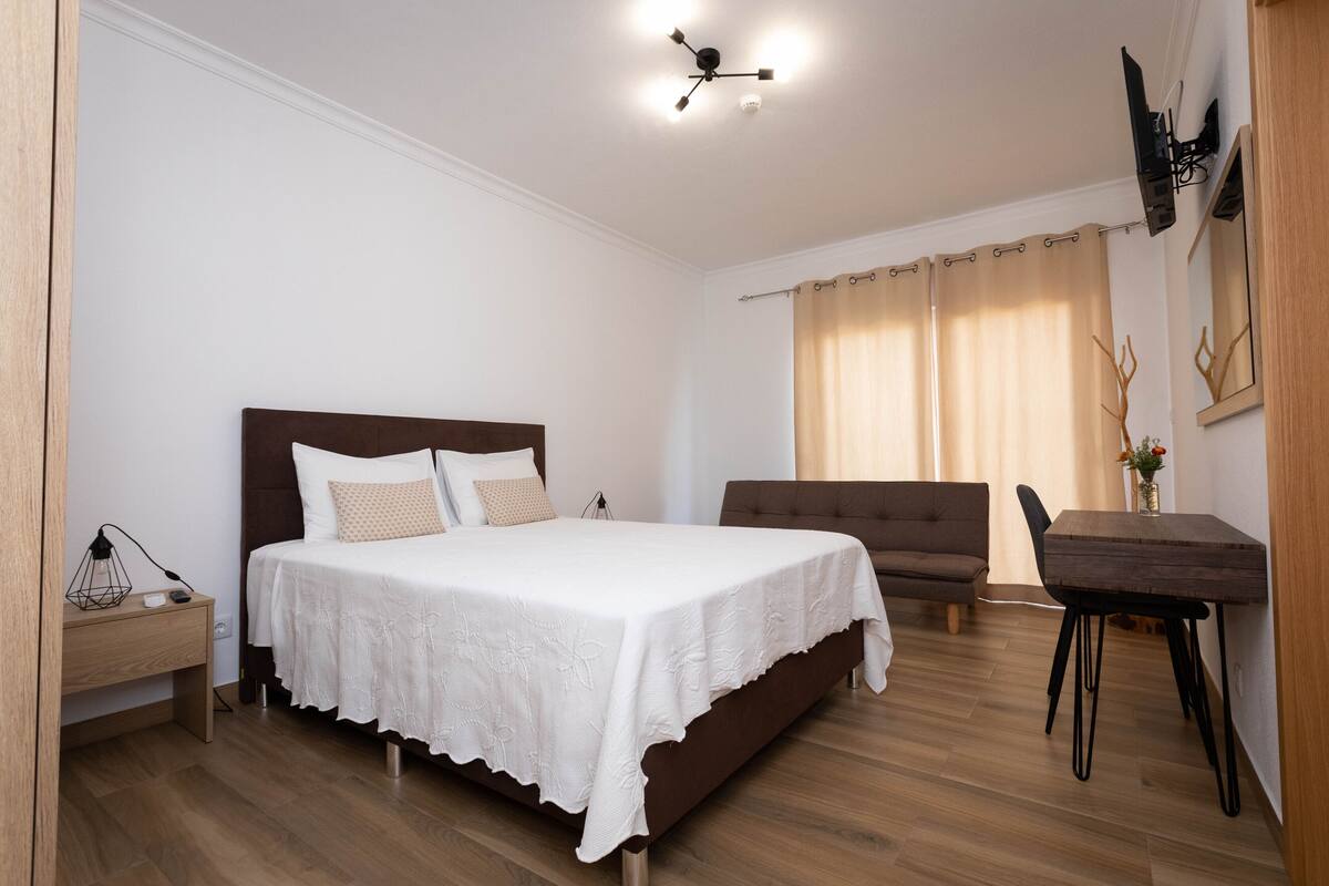 Ein Schlafzimmer mit einem Bett, einer Couch, einem Holztisch und einem Schreibtisch.