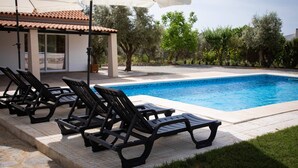 Une piscine avec des chaises longues et un espace abrité.