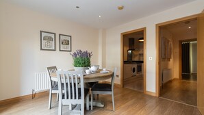 A dining area with a round table, white chairs, a potted plant, and framed pictures on the wall. - Charming Leopardstown Townhouse (Dublin)