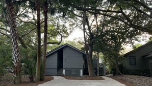 A building with a grey exterior, a staircase leading to the entrance, and a paved driveway.