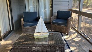 A porch with wicker furniture and a small sailboat model.