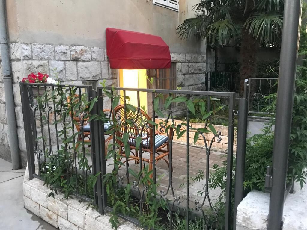 Un patio con cerca de metal, una silla de mimbre y un paraguas rojo.