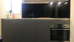 Uma cozinha compacta com micro-ondas, forno e uma pequena bancada.
