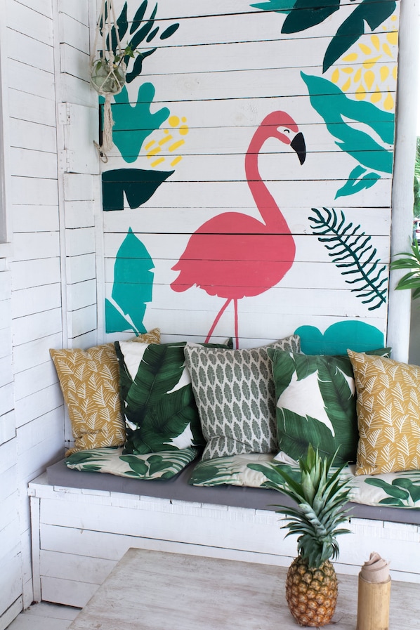 Un banc en bois agrémenté de coussins aux motifs tropicaux et d’une décoration en forme d’ananas.