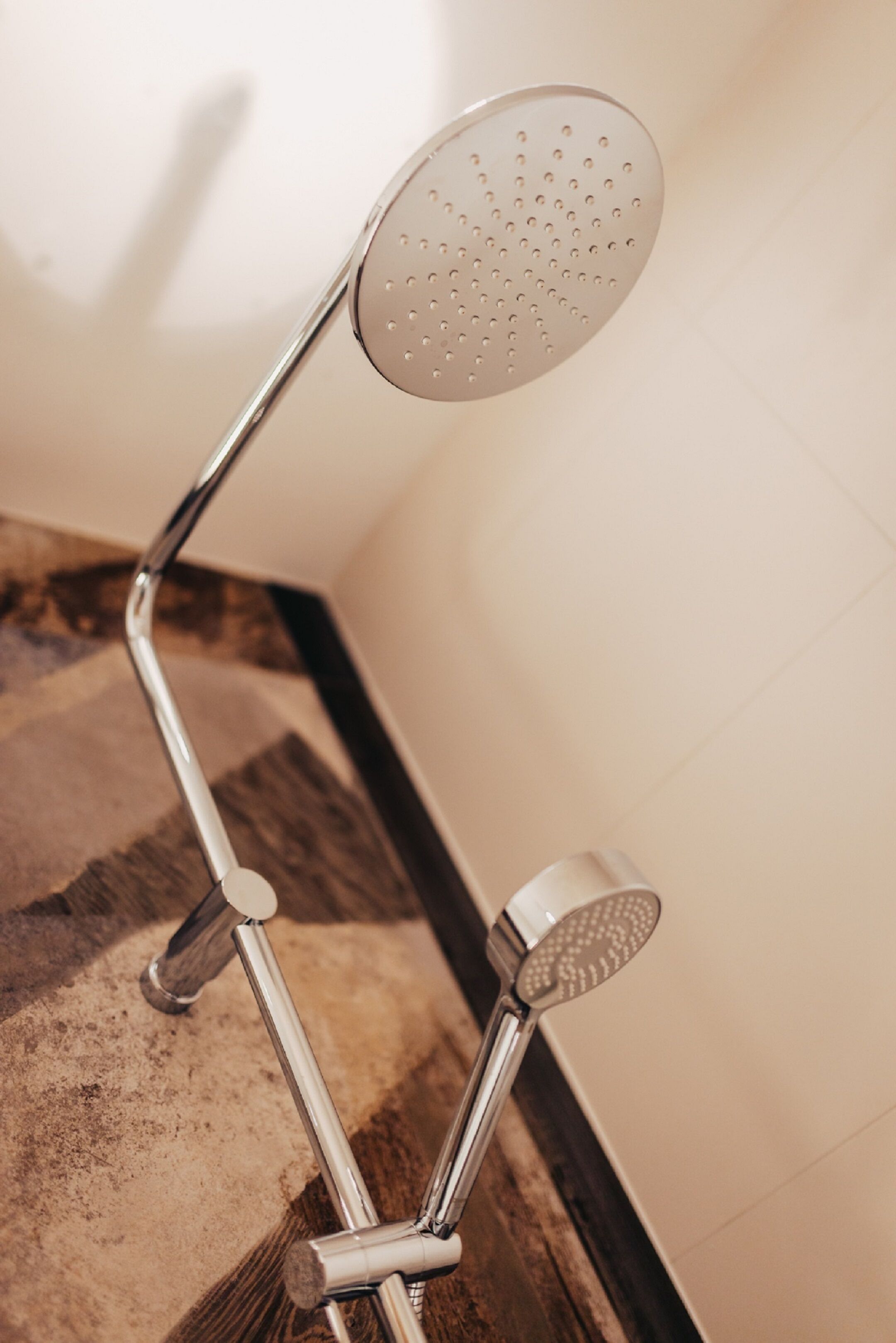 Un pommeau de douche de forme ronde et perforée, fixé sur un support métallique.