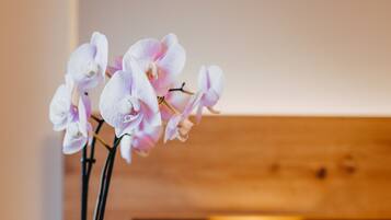 Eine weiße Orchidee im Topf auf einem hölzernen Nachttisch in einem Hotelzimmer.