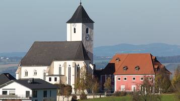 Une église dotée d’un clocher et d’un bâtiment à toit rouge, située dans un cadre rural.