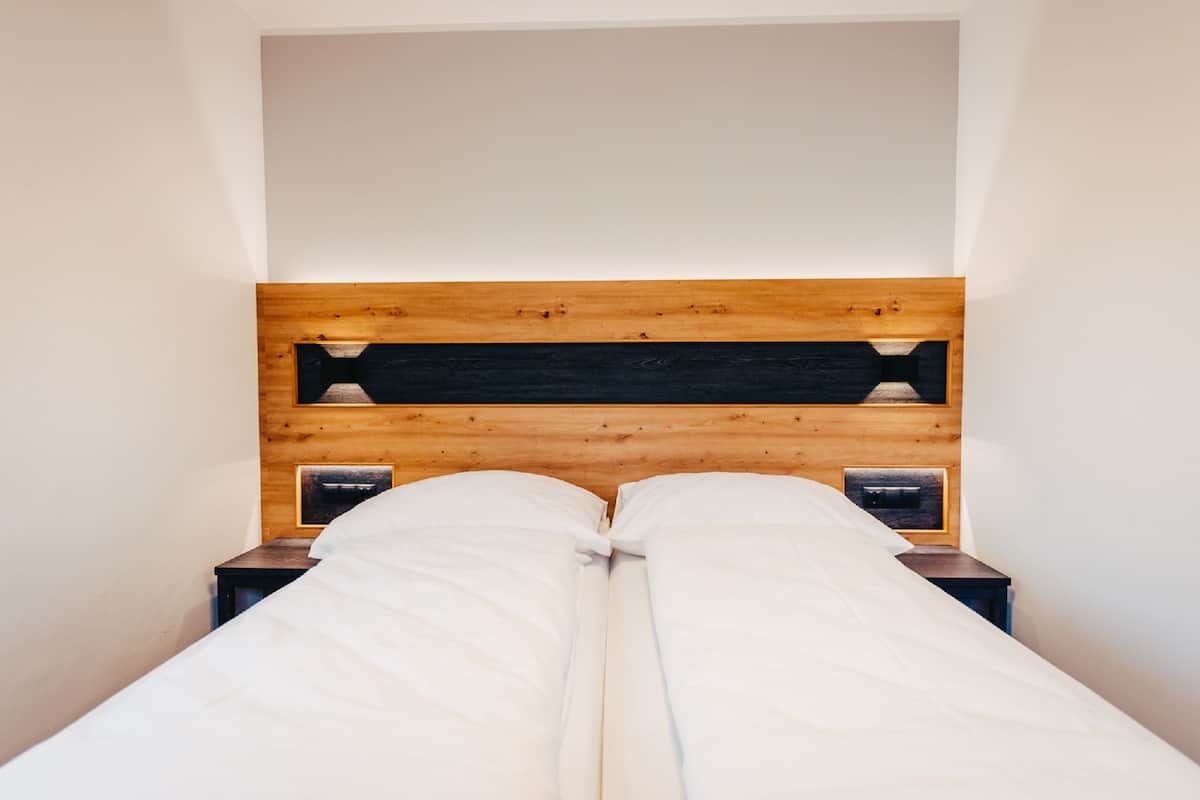 Una cama doble con cabecera de madera, dos mesitas de noche y un pequeño estante.