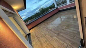 A wooden deck with a view of a building and trees.