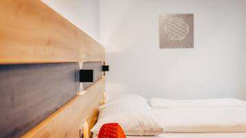 Un lit avec une tête de lit en bois, une literie blanche et un luminaire fixé au mur.
