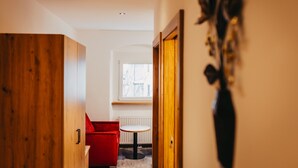 A hallway with a wooden wardrobe, a red chair, a small round table, and a radiator.